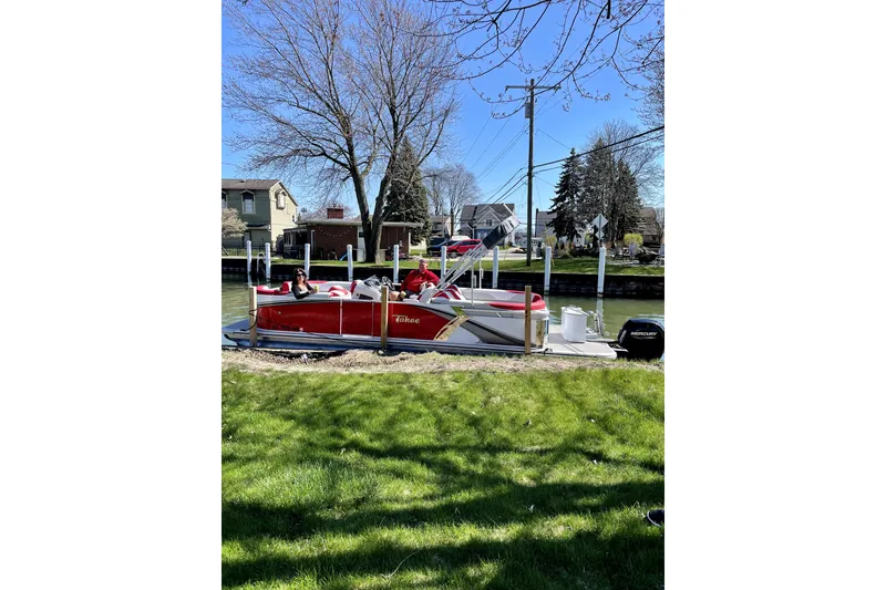 Slide: The Image of 2023 Tahoe Pontoon 2385 Cascade Quad Lounger docked by a grassy shoreline. - 2