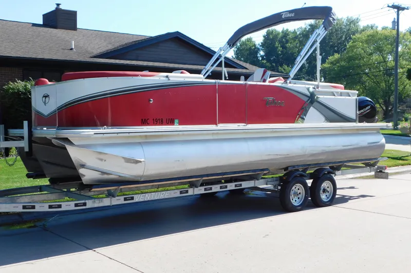 Slide: The Image of 2023 Tahoe Pontoon 2385 LTZ Quad Lounger on trailer, red and silver design. - 1