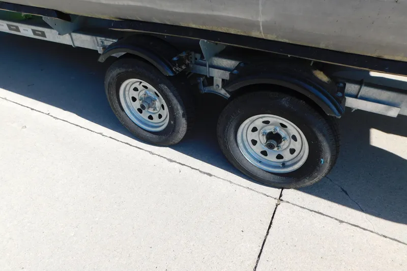 Slide: The Image of Trailer wheels of a 2023 Tahoe Pontoon 2385 LTZ Quad Lounger on pavement. - 56