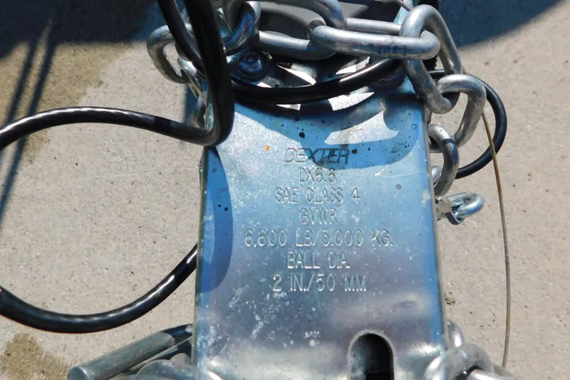 Slide: The Image of Trailer hitch with chains, showing Dexter branding and specifications for towing capacity. - 53