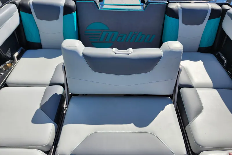 Slide: The Image of 2022 Malibu M220 boat interior with gray and teal seating, featuring the Malibu logo. - 24