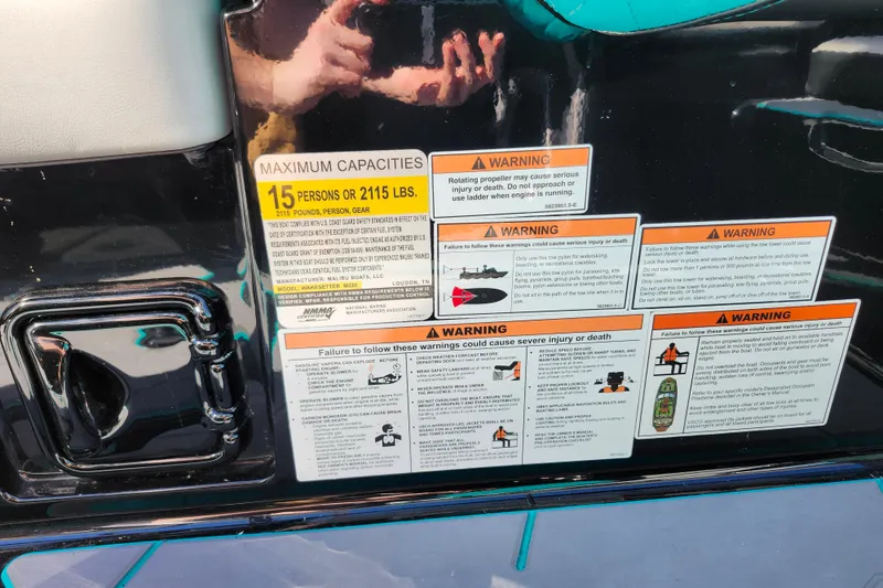 Slide: The Image of 2022 Malibu M220 boat warning labels and capacity information, 15 persons or 2115 lbs. - 33