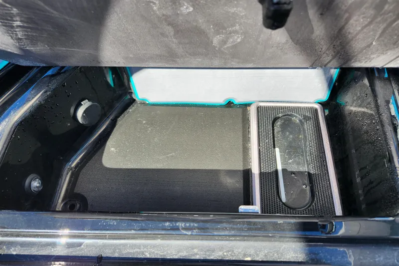 Slide: The Image of 2022 Malibu M220 storage compartment with black interior and drainage feature. - 34