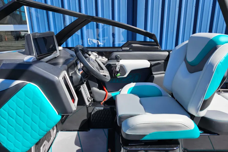 Slide: The Image of 2022 Malibu M220 boat interior with modern dashboard and teal-accented seating. - 36