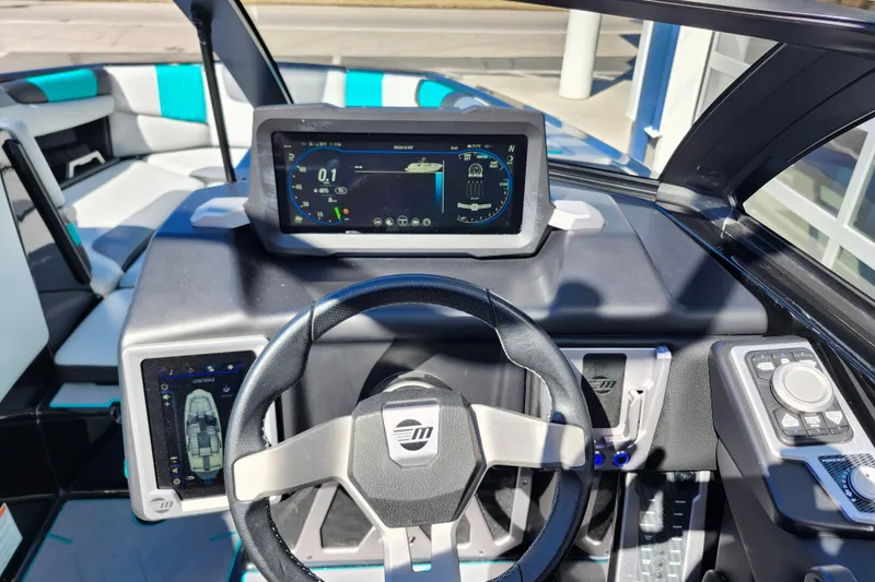 Slide: The Image of 2022 Malibu M220 boat dashboard with steering wheel and digital display. - 37