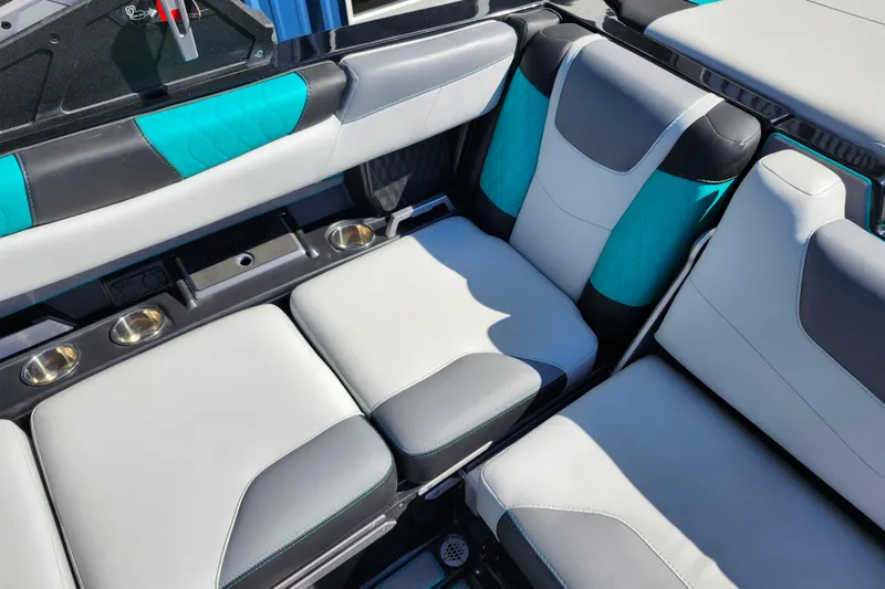 Slide: The Image of 2022 Malibu M220 boat interior with teal and gray seating, featuring cup holders. - 41