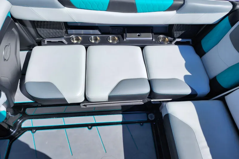 Slide: The Image of 2022 Malibu M220 boat interior with white and teal seating and cup holders. - 42