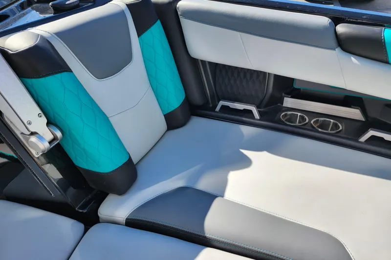 Slide: The Image of 2022 Malibu M220 boat interior with teal and gray seating, featuring cup holders. - 46