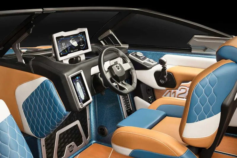 Slide: The Image of 2022 Malibu M220 boat with teal and silver accents, parked outdoors near a blue building. - 7