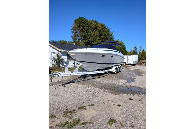 Slide: The Image of 1998 Cobalt 293 boat on trailer, parked outdoors under clear blue sky. - 3