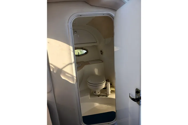 Slide: The Image of Interior of 1998 Cobalt 293 boat showing compact bathroom with toilet and porthole window. - 33