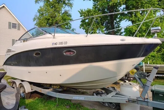 The Image of 2009 Maxum 2700 SE boat on trailer, parked outdoors near trees and a house. - 0
