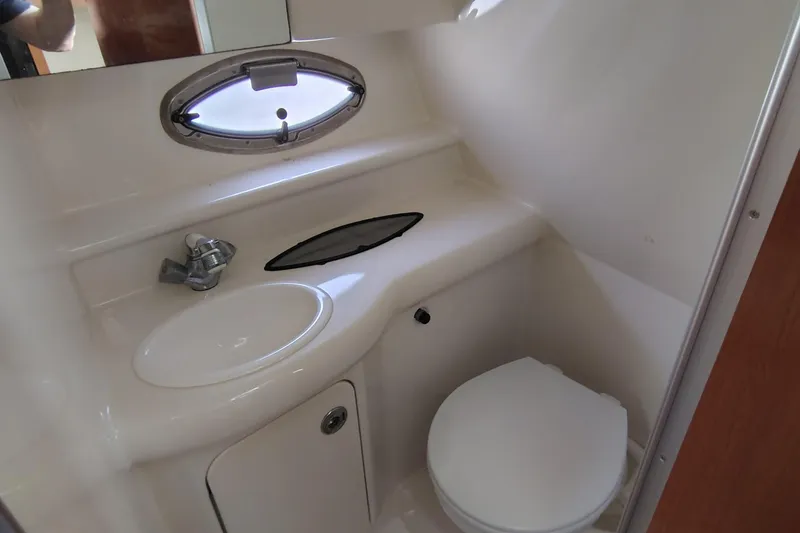 Slide: The Image of 2009 Maxum 2700 SE boat bathroom with sink, toilet, and porthole window. - 10
