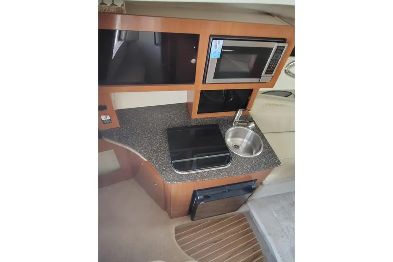 Slide: The Image of Compact kitchen area in 2009 Maxum 2700 SE boat with microwave, sink, and stove. - 11