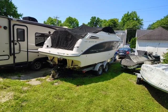 Slide: The Image of 2009 Maxum 2700 SE boat on trailer, parked beside RV, outdoors. - 2