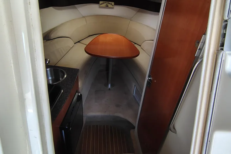 Slide: The Image of 2009 Maxum 2700 SE cabin interior with seating, table, and kitchenette. - 8