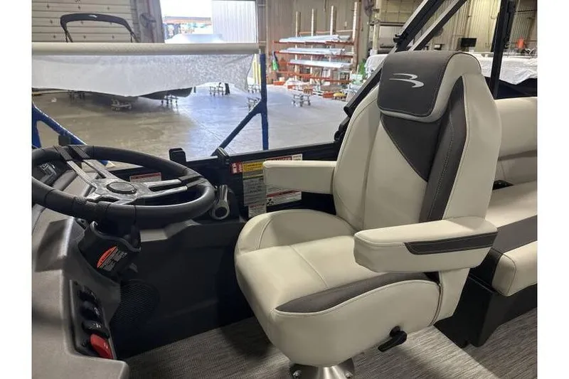 Slide: The Image of 2026 Bennington 20 SSR Tritoon captain's chair and steering wheel in a showroom. - 9