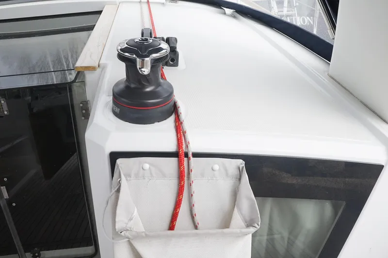 Slide: The Image of Deck view of 2021 Beneteau Oceanis 38.1 sailboat with winch and red rope. - 46