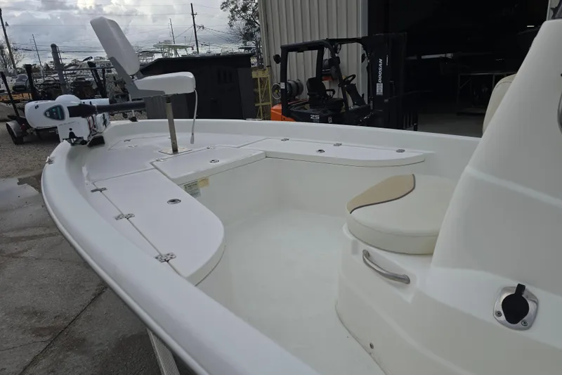 Slide: The Image of 2018 NauticStar 2140 Sport boat with seating and trolling motor, parked outdoors. - 10