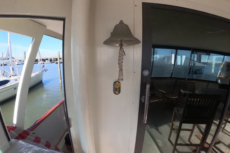 Slide: The Image of 1987 Hatteras 54 Motor Yacht interior with nautical bell and marina view. - 34