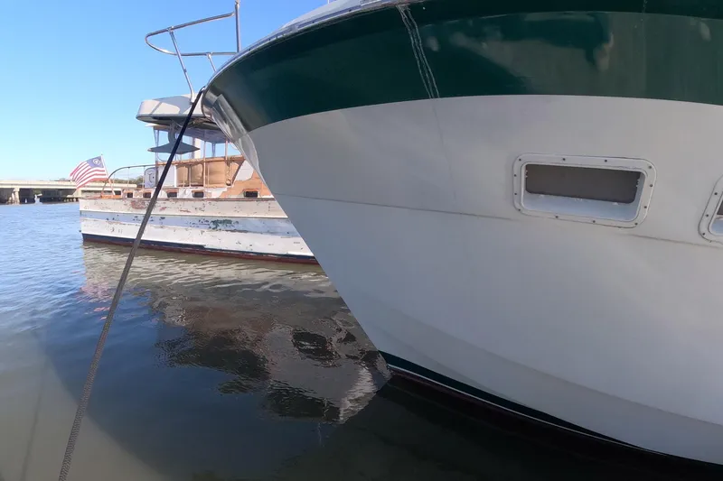 Slide: The Image of 1987 Hatteras 54 Motor Yacht docked beside another boat on calm water. - 35