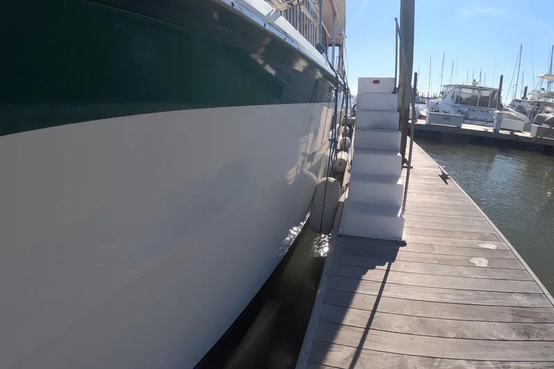 Slide: The Image of 1987 Hatteras 54 Motor Yacht docked with boarding stairs, sunny marina setting. - 36