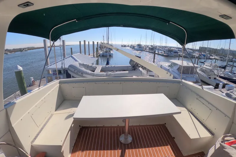 Slide: The Image of 1987 Hatteras 54 Motor Yacht deck with table, marina view, and green canopy. - 41
