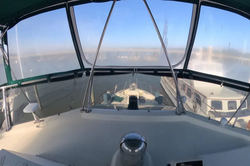 Slide: The Image of 1987 Hatteras 54 Motor Yacht helm view with clear canopy and marina backdrop. - 45