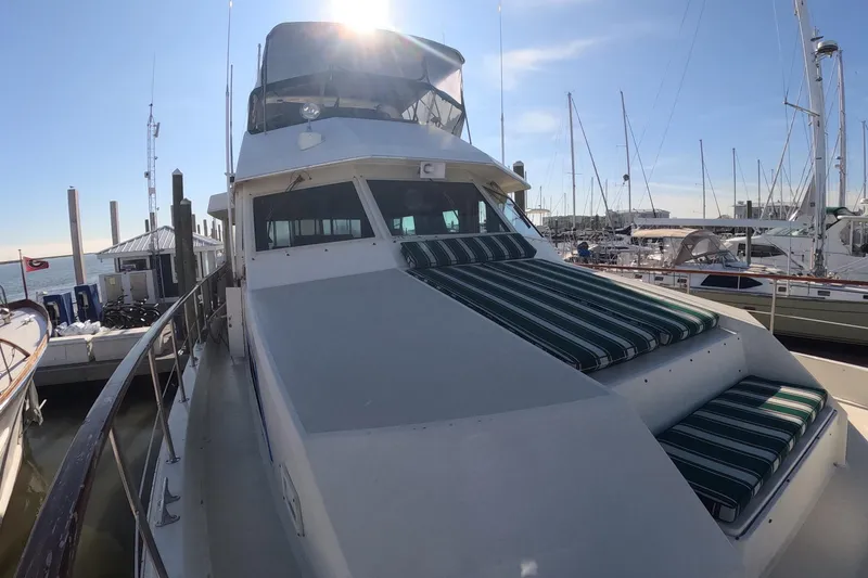 Slide: The Image of 1987 Hatteras 54 Motor Yacht docked at marina, featuring striped deck cushions. - 48