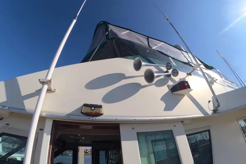 Slide: The Image of 1987 Hatteras 54 Motor Yacht with dual horns and canopy under clear blue sky. - 52