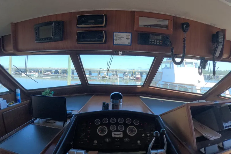 Slide: The Image of 1987 Hatteras 54 Motor Yacht helm with navigation equipment and marina view. - 6