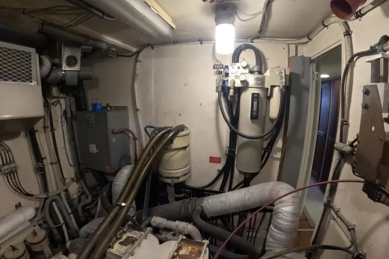 Slide: The Image of Engine room of a 1987 Hatteras 54 Motor Yacht, showcasing mechanical components and wiring. - 60