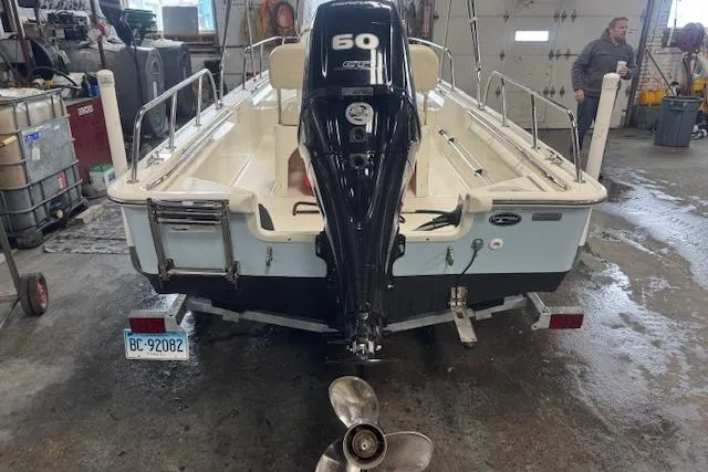 Slide: The Image of 2024 Boston Whaler 150 Montauk boat in a garage, rear view with outboard motor. - 10