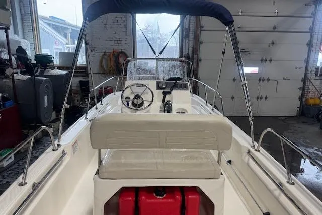 Slide: The Image of 2024 Boston Whaler 150 Montauk boat interior in a garage setting. - 9