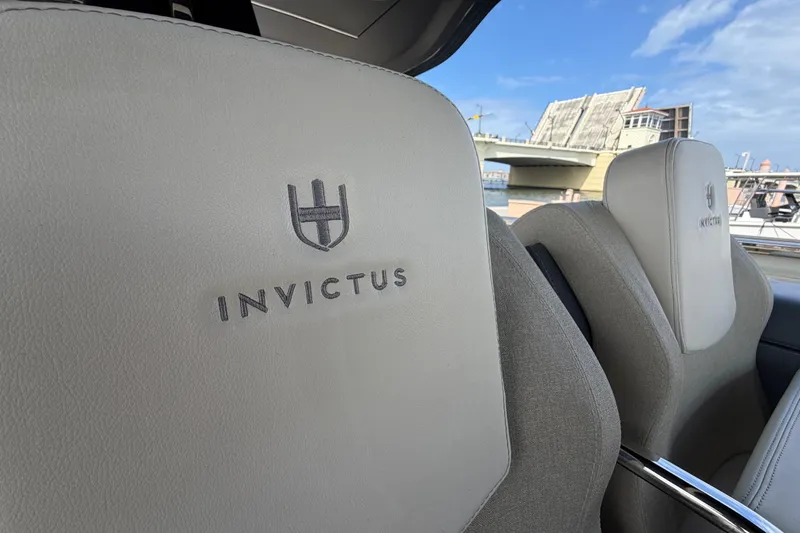 Slide: The Image of 2024 Invictus TT460 boat seats with logo, bridge in background, clear sky. - 19