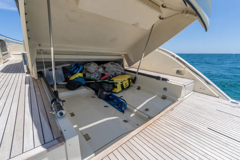 Slide: The Image of Open storage compartment on 2024 Invictus TT460 yacht, revealing gear and equipment, with ocean backdrop. - 54