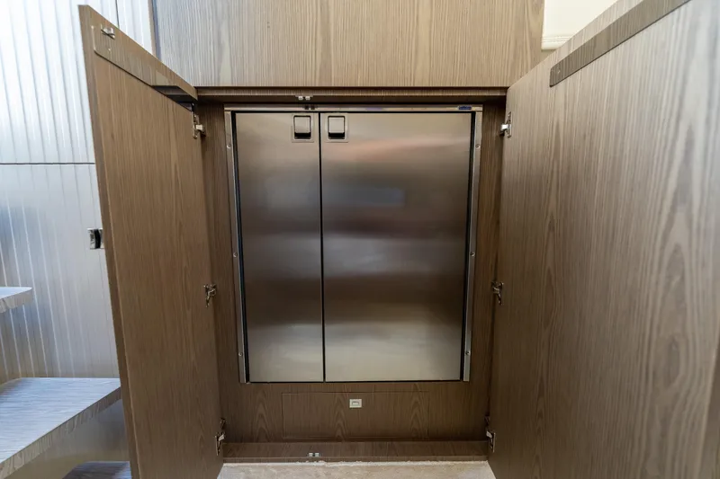 Slide: The Image of 2024 Invictus TT460 yacht interior with sleek stainless steel refrigerator and wooden cabinetry. - 67