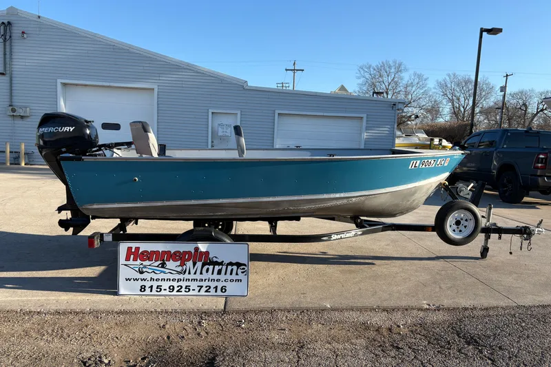 The Image of 1995 Lund 1440-V Rebel Tiller boat on trailer at Hennepin Marine dealership. - 1