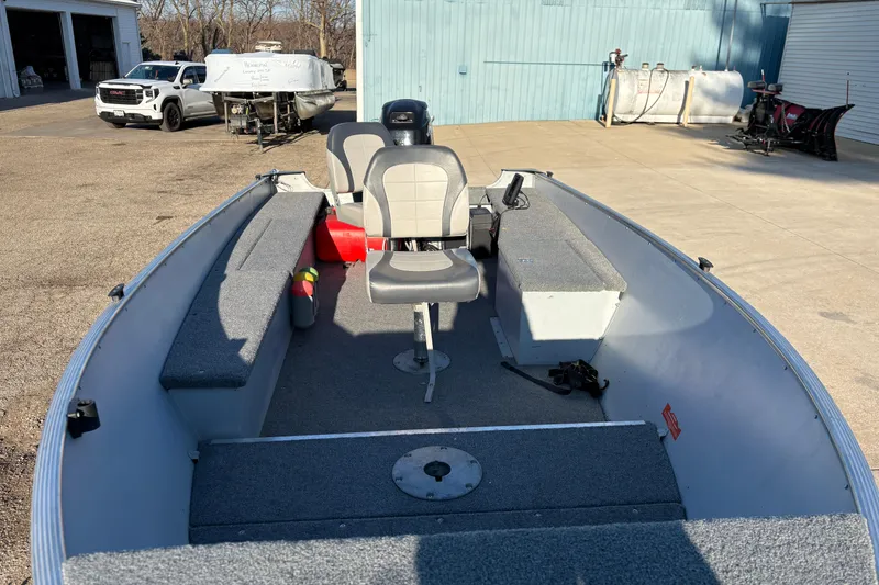 Slide: The Image of 1995 Lund 1440-V Rebel Tiller boat with seating and storage, parked outdoors. - 9
