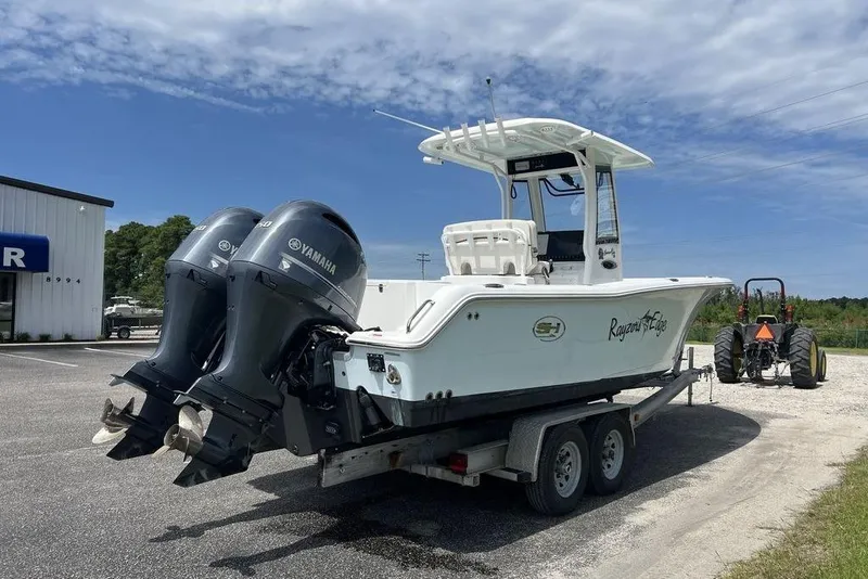 Slide: The Image of 2026 Sea Hunt Gamefish 25 boat on trailer with dual Yamaha engines, parked outdoors. - 9