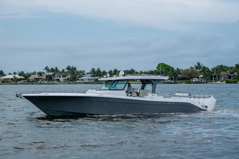 Slide: The Image of HCB 48 Campeon 2025 boat cruising on a calm waterway with houses in the background. - 11