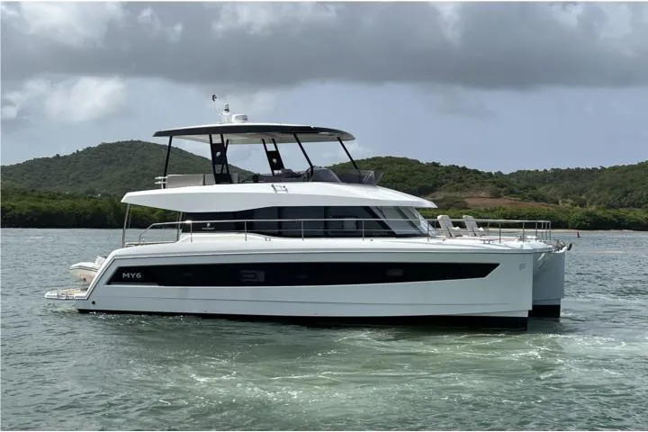 Slide: The Image of 2024 Fountaine Pajot Motor Yacht 44 on water, sleek design, sunny day, palm trees in background. - 2