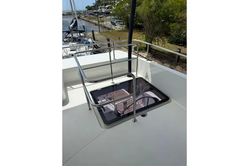 Slide: The Image of 2024 Fountaine Pajot MY6 yacht deck with hatch and railing, docked near lush greenery. - 33