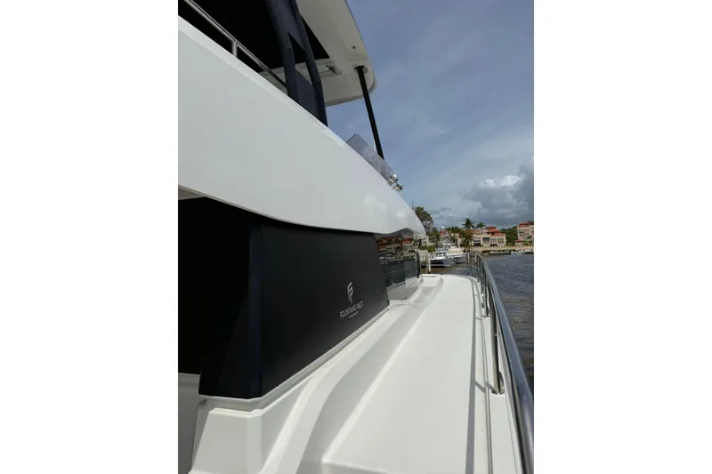 Slide: The Image of 2024 Fountaine Pajot MY6 yacht side view, sleek design, docked near waterfront homes. - 43