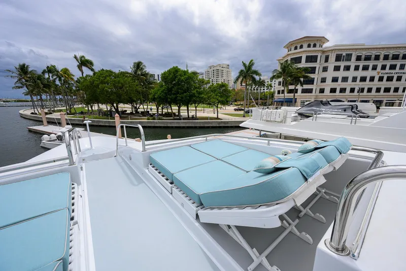 Slide: The Image of Luxurious 2003 Cheoy Lee Trideck yacht with sun loungers, docked near palm trees and buildings. - 64