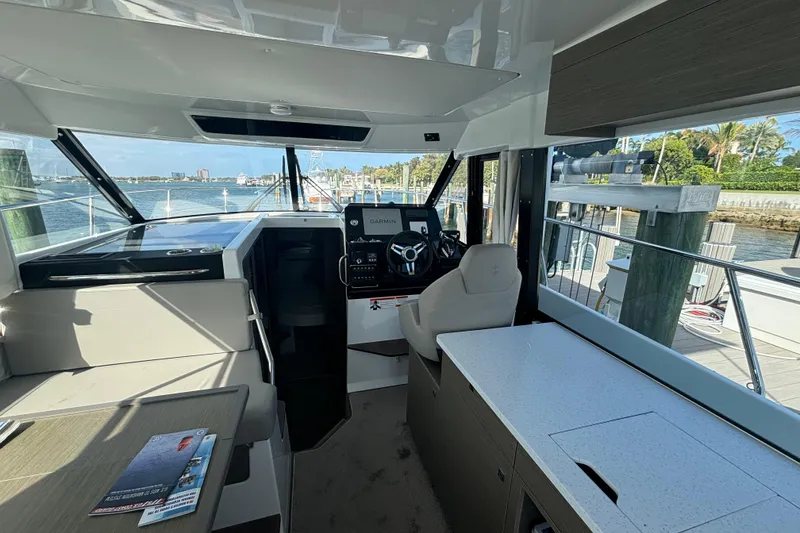 Slide: The Image of 2024 Jeanneau NC Weekender 1095 Fly interior with helm, seating, and waterfront view. - 15