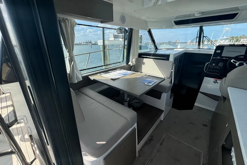 Slide: The Image of 2024 Jeanneau NC Weekender 1095 Fly interior with dining area and helm, overlooking marina. - 12