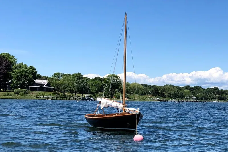 Slide: The Image of 2018 Ballentine's Boat Shop Doughdish sailboat moored on a scenic lake. - 2