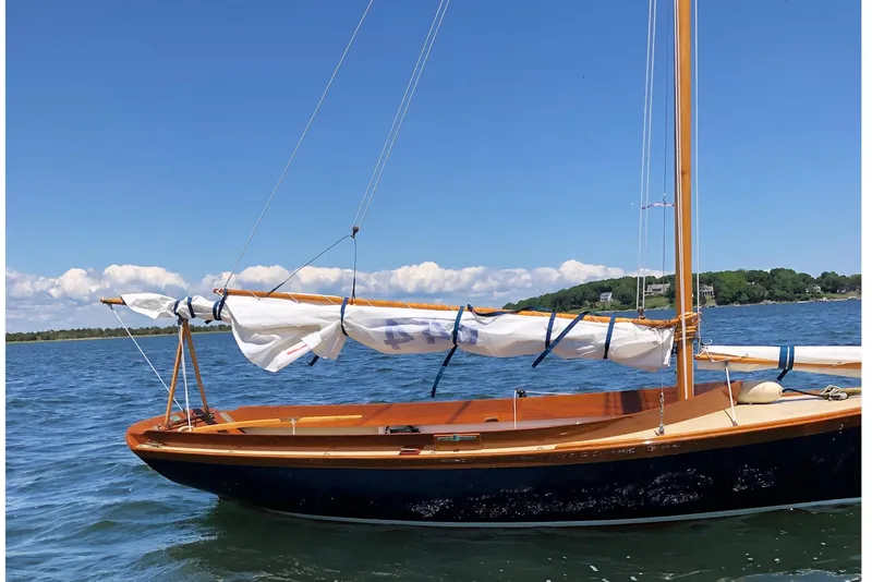 Slide: The Image of 2018 Ballentine's Boat Shop Doughdish sailboat on calm water under clear blue sky. - 25