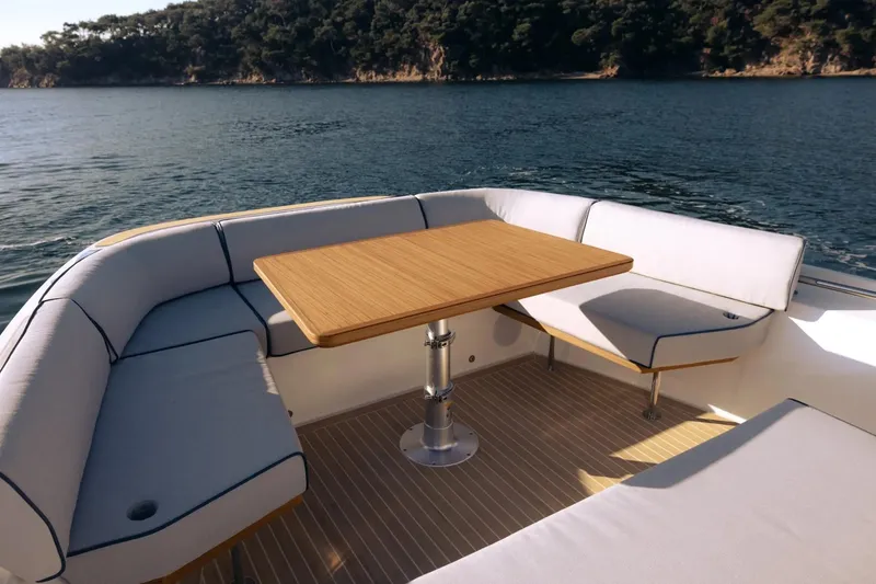 Slide: The Image of Luxurious seating area on 2026 Aiata Wayfinder 38 yacht, featuring a wooden table and scenic water view. - 11